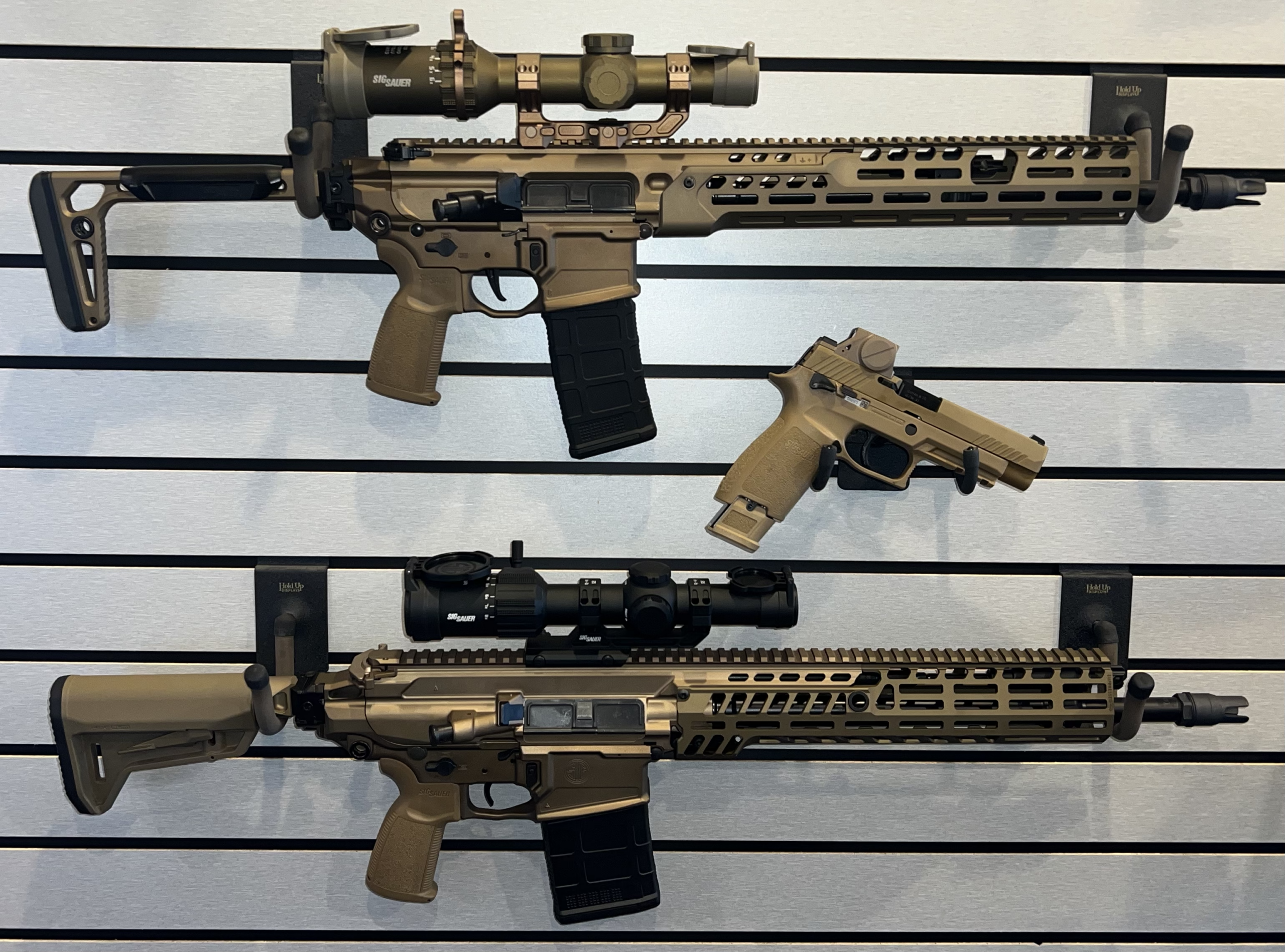 Tan AR-style rifles and pistol on display