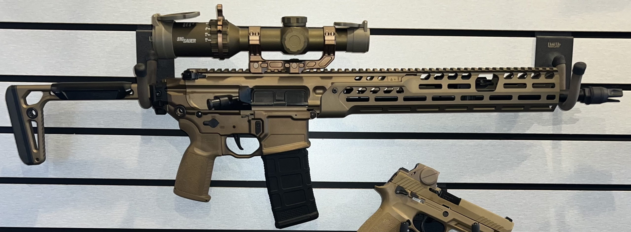Tan AR-style rifle with scope and pistol